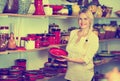 Portrait of glad woman choosing glazed with red color ceramic ut Royalty Free Stock Photo