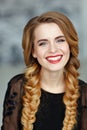 Portrait of a glamorous beautiful girl with bright makeup in black dress and braids, laughing, studio, close-up