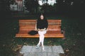 Portrait of a glamorous young woman holding on her knees a book while sitting on a wooden bench. Soft colours, awesome place