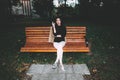 Portrait of a glamorous young woman holding on her knees a book while sitting on a wooden bench. Soft colours, awesome place