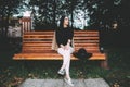 Portrait of a glamorous young woman holding on her knees a book while sitting on a wooden bench. Soft colours, awesome place