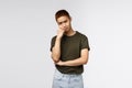 Portrait of gloomy, sad asian guy in green t-shirt, pouting and looking camera upset, lean on palm, feeling uneasy about Royalty Free Stock Photo