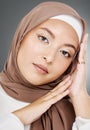 Portrait of a glowing elegant muslim womans face isolated against grey studio background. Young woman wearing a hijab or Royalty Free Stock Photo