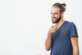 Portrait of good-looking bearded man with great hairdo pointing with index finger in camera and brightfully smiling Royalty Free Stock Photo