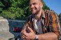 Portrait of good looking bold bearded guy outdoors holding cellphone in his hand with earphones in his ears and listening music Royalty Free Stock Photo