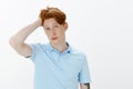 Portrait of good-looking confident male redhead with freckles, gazing at camera and touching hair, trying to look