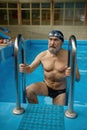 Portrait of good-looking fit senior man getting out from swimming pool Royalty Free Stock Photo