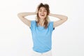 Portrait of good-looking positive woman in blue t-shirt and white jeans, holding hands on head and smiling broadly Royalty Free Stock Photo