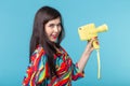 Portrait of a smiling young woman with a vintage yellow video camera in her hands posing against a blue background