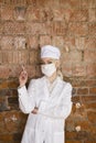 Portrait of a good looking young blond nurse with disposable syringe in her arms in a red brick background. Royalty Free Stock Photo