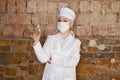 Portrait of a good looking young blond nurse with disposable syringe in her arms in a red brick background. Royalty Free Stock Photo