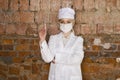 Portrait of a good looking young blond nurse with disposable syringe in her arms in a red brick background. Royalty Free Stock Photo