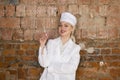 Portrait of a good looking young blond nurse with disposable syringe in her arms in a red brick background. Royalty Free Stock Photo