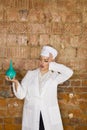 Portrait of a good looking young nurse with enema in her arms in a brick red background. Medical concept. Royalty Free Stock Photo