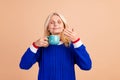 Portrait of good mood person with blond hair wear blue pullover smell cup of aromatic tea eyes closed isolated on beige Royalty Free Stock Photo