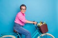 Portrait of good mood senior person with grey hair wear stylish blouse riding bicycle with flowers isolated on blue