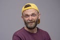 Portrait of a good-natured man 45-50 years old with a beard and a yellow cap on a gray background. Concept: illegal construction w
