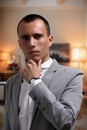 Portrait of goodlooking thoughtful young businessman in gray jacket and white t-shirt, looking at camera