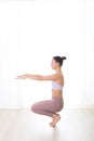 Portrait of gorgeous active sporty young woman practicing yoga in studio. Beautiful girl practice Utkatasana, awkward