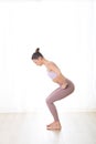 Portrait of gorgeous active sporty young woman practicing yoga in studio. Beautiful girl practice Utkatasana, awkward