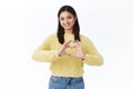 Portrait of gorgeous asian girl showing heart sign and smiling happy. Woman express her feelings and sympathy, cherish