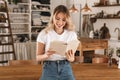 Portrait of gorgeous blond woman reading book while standing in stylish wooden kitchen at home