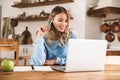 Portrait of gorgeous blond woman 20s wearing casual sweatshirt working on laptop and writing down notes at home Royalty Free Stock Photo