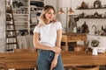 Portrait of gorgeous blond woman smiling and rejoicing while standing in stylish wooden kitchen at home