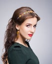 Portrait of gorgeous brunette wearing luxury golden coronet and earrings