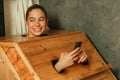 Gorgeous woman playing her mobile phone while using sauna cabinet.Tranquility Royalty Free Stock Photo