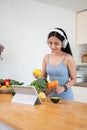 A gorgeous and fit Asian woman enjoys the music while preparing her healthy breakfast in the kitchen Royalty Free Stock Photo