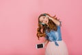 Portrait of gorgeous happy long-haired girl in headphones singing favorite song isolated on pink background. Attractive