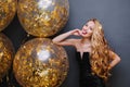 Portrait gorgeous playful young woman with long curly blonde hair having fun with big balloons full with golden tinsels Royalty Free Stock Photo