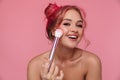 Portrait of gorgeous shirtless woman applying cosmetics with makeup brush