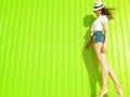 Portrait of gorgeous slim long-legged model with long waving hair wearing white panama, blouse and trendy jeans shorts