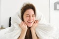 Portrait of gorgeous smiling woman, lying in bed covered in duvet, has messy hair, looking happy, relaxing in her Royalty Free Stock Photo
