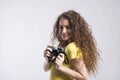 Portrait of a gorgeous teenage girl with curly hair holding camera. Studio shot, white background with copy space