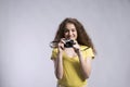 Portrait of a gorgeous teenage girl with curly hair holding camera. Studio shot, white background with copy space