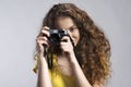 Portrait of a gorgeous teenage girl with curly hair holding camera. Studio shot, white background with copy space