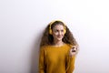 Portrait of a gorgeous teenage girl with curly hair, listening music via headphones. Studio shot, white background with Royalty Free Stock Photo