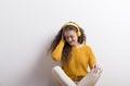 Portrait of a gorgeous teenage girl with curly hair, listening music via headphones. Studio shot, white background with Royalty Free Stock Photo