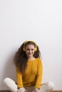 Portrait of a gorgeous teenage girl with curly hair, listening music via headphones. Studio shot, white background with Royalty Free Stock Photo