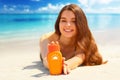 Portrait of gorgeous woman smiling while relaxing on beach and holding sunscreen bottle Royalty Free Stock Photo
