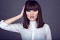 Portrait of gorgeous young dark-haired woman looking straight and touching hair with her hand.