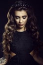 Portrait of gorgeous young model with dark long silky wavy hair, thick eyelashes and full lips wearing lace dress and jewel crown