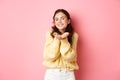 Portrait of gorgeous young woman with bright make up, holding on palms, smiling and demonstrating something in her hands Royalty Free Stock Photo