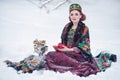 Portrait of a gorgeous young woman in russian style dress on a strong frost in a winter snowy day with apples and samovar.