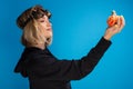 Portrait of goth girl wearing steam punk glasses looking confident at an orange carved pumpkin