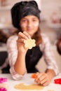 Portrait of grandchild wearing apron looking into camera while holding cookie dough