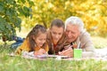 Portrait of grandchildren and grandfather doing homework in park